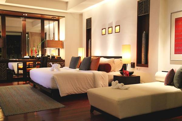 Schlafzimmer im Mai Samui Beach Resort & Spa mit einem großen Bett, Kissen, Lampen und einem Teppich.