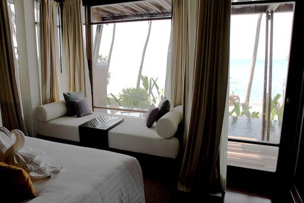Zimmer im Mai Samui Beach Resort mit Bett und Fenster, das auf den Ozeanblick zeigt.