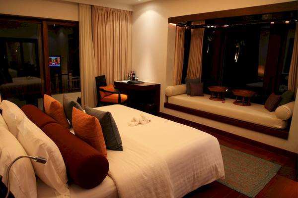 Schlafzimmer im Mai Samui Beach Resort & Spa mit Bett, Fenstern und Schreibtisch.