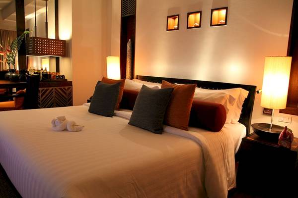 Bett im Mai Samui Beach Resort & Spa mit Kissen und Decken, Nachttisch und Lampen.