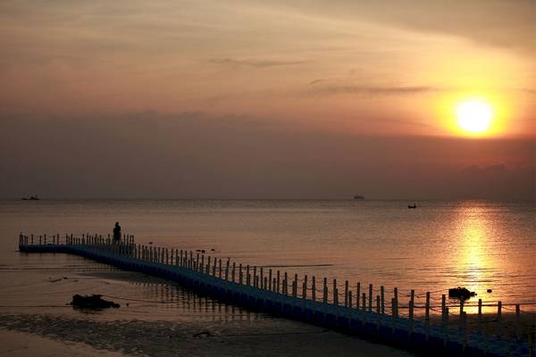 Sonnenuntergang am Strand mit Steg und Person