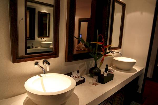 Badezimmer im Mai Samui Beach Resort & Spa mit zwei Waschbecken, Spiegeln und Pflanzen.