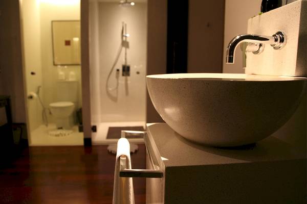 Ein Badezimmer mit einer Dusche und einem Waschbecken, das an einer Wand befestigt ist.