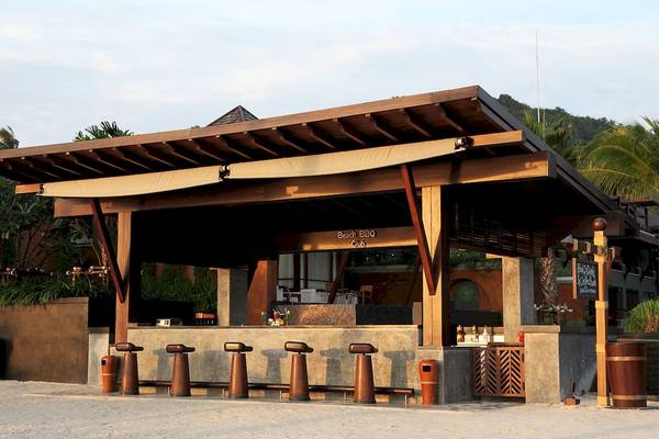 Außenbereich des Beach BBQ Clubs im Mai Samui Beach Resort & Spa mit Holzstühlen und einem gedeckten Tisch.