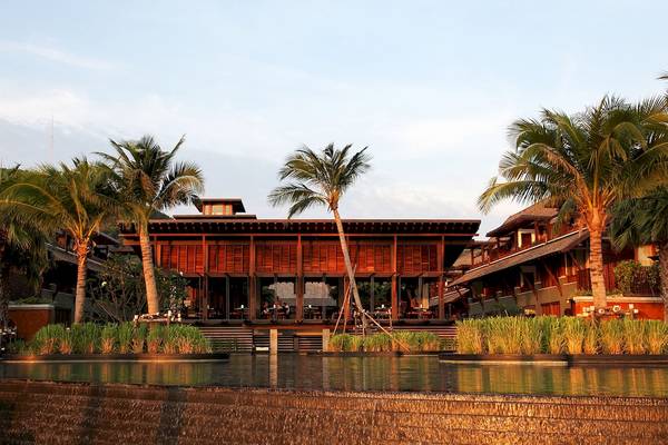 Außenansicht des Mai Samui Beach Resorts mit Gebäuden, Palmen und Wasserfall.