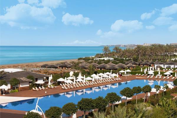 Außenbereich des Maxx Royal Belek Golf Resorts mit großen Pool, Lounge-Stühlen und Blick aufs Meer