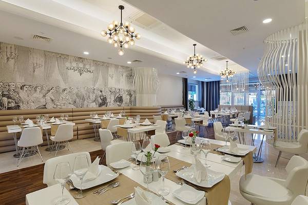 Restaurantbereich des Seashell Resort & Spa mit weißen Tischen und Stühlen, dekorativen Wandgemälden und Kronleuchtern.