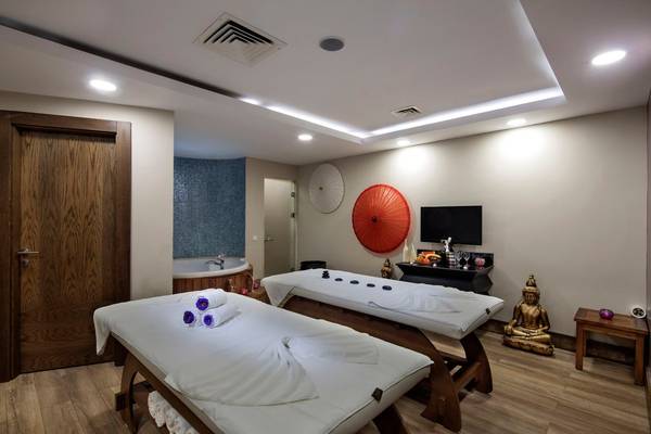 Massageraum im Seashell Resort & Spa mit zwei Massagetischen, einem Whirlpool und einer Buddha-Statue.
