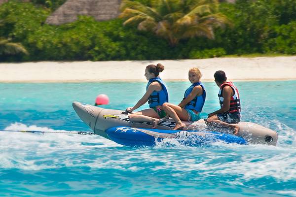 Drei Personen genießen eine Bootsfahrt im Wasser bei Villa Nautica Paradise Island Resort.