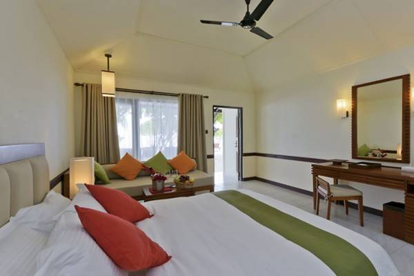 Innenansicht eines Hotelzimmers im Villa Nautica Paradise Island Resort mit Bett, Sofa, Fernseher und Schreibtisch.