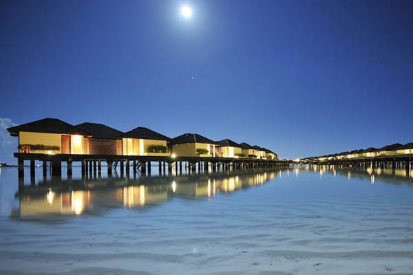 Villa Nautica Paradise Island Resort bei Nacht mit leuchtenden Wasservillen und Vollmond am Himmel.