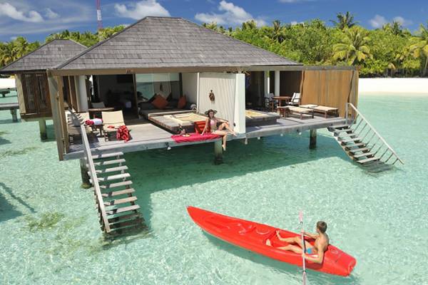 Wasservilla des Villa Nautica Paradise Island Resorts mit Personen auf der Veranda und einem Kanu im Wasser.