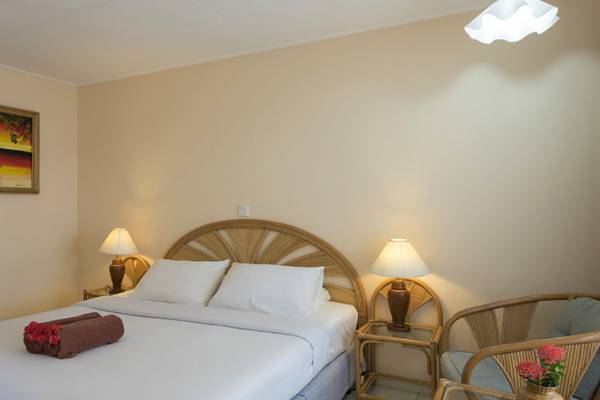 Ein geräumiges Hotelzimmer mit Bett, Nachttischen, Lampen und einem Gemälde an der Wand.