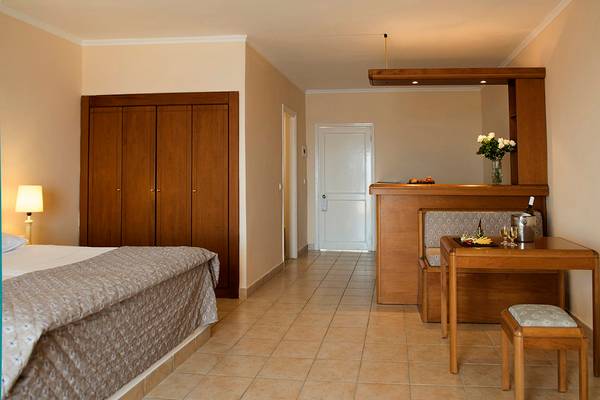 Schlafzimmer im Mitsis Family Village Beach Hotel mit Bett, Schrank, Tisch und Dekoration.