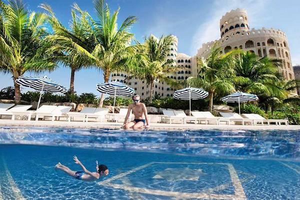 Mann und Kind schwimmen im Pool des Al Hamra Residence Hotels.