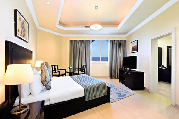 Hotelzimmer von Al Hamra Residence mit Bett, Fernseher und Meerblick.