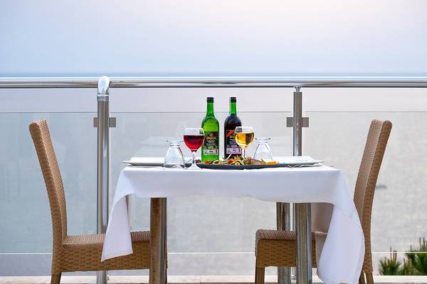 Ein Tisch mit Getränken und Essen auf einer Terrasse mit Blick auf das Meer.