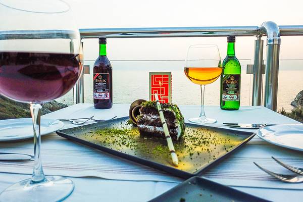 Auf der Terrasse des Ladonia Hotels Adakule stehen zwei Gläser Wein, eine Flasche Likör und ein Dessert auf einem Tisch.