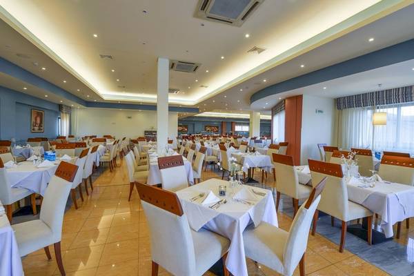 Innenbereich des Restaurants im Mediterranean Beach Resort mit vielen gedeckten Tischen und Stühlen.