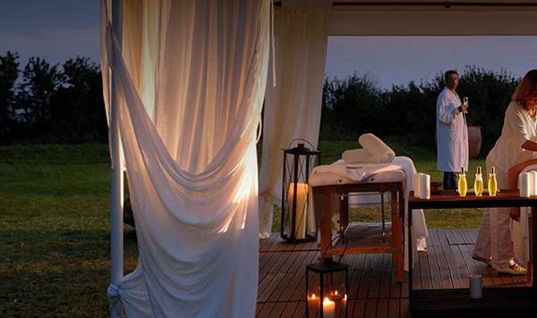 Spa-Massage auf der Terrasse im Coral Beach Hotel & Resorts mit zwei Frauen, weiße Vorhänge und Kerzen.