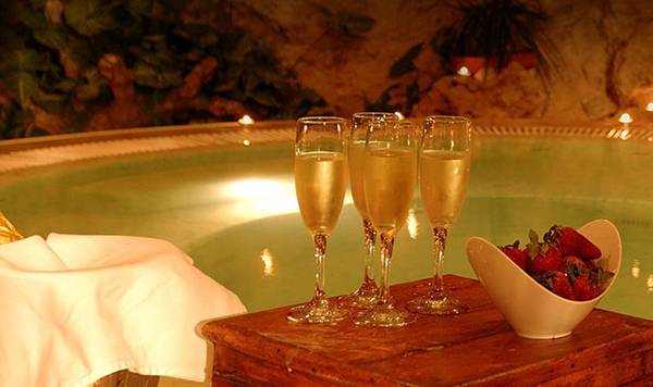 Eine Frau genießt ein Getränk in einem beleuchteten Whirlpool mit Champagner und Erdbeeren.