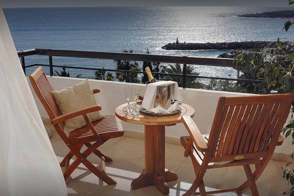 Balkon des Coral Beach Hotel mit Blick auf das Meer und einem Tisch mit Champagner und Gläsern.