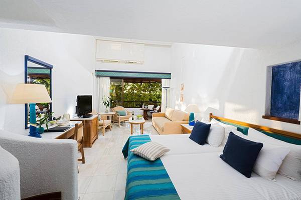 Suite-Zimmer im Coral Beach Hotel & Resorts mit Balkon, Bett, Sofa und Tisch.