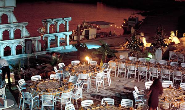 Abendessen am Pool im Coral Beach Hotel & Resorts mit vielen runden Tischen und Stühlen, umgeben von Dekoration.