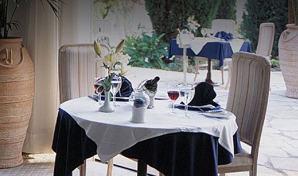 Innenansicht des Restaurants im Coral Beach Hotel mit Tisch, Stühlen und großen Vasen.