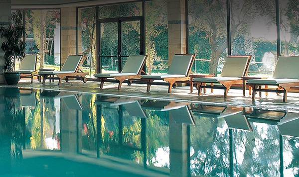 Innenpool des Coral Beach Hotel & Resorts mit Lounge-Sesseln und Pflanzen.