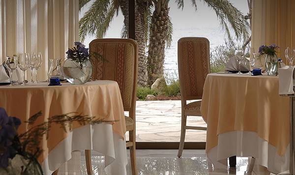 Innenansicht eines elegant eingerichteten Restaurants im Coral Beach Hotel mit Blick auf das Meer.