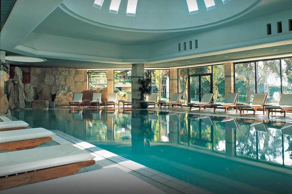 Coral Beach Hotel & Resorts Pool mit Loungeliegen und großer Fensterfront.