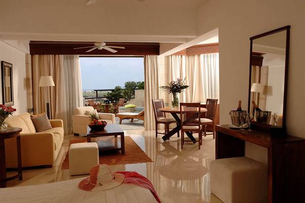 Innenansicht einer Suite im Coral Beach Hotel mit Wohnzimmer, Essbereich und Blick auf den Außenbereich.