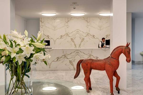 Lobby des Barceló Teguise Beach Adults Only Hotels mit Rezeption, rotem Pferdestatue und weißen Lilien im Glasvase.