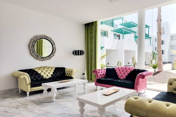 Hotelloungebereich des Barceló Teguise Beach mit bunten Sofas, Tisch und spiegelverzierten Wänden.