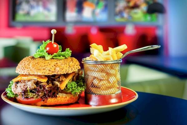 Ein Burger mit Salat, Tomaten und Pommes in einem Restaurant serviert.