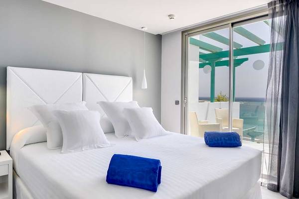 Zimmer im Barceló Teguise Beach Adults Only Hotel mit einem Bett, weißen Kissen und blauen Handtüchern.