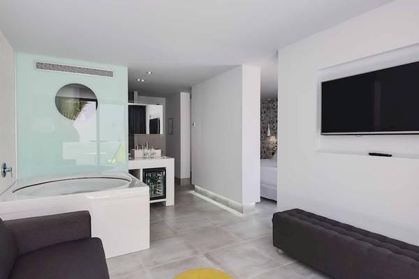 Innenansicht der Suite im Barceló Teguise Beach Hotel mit Badewanne, Fernseher und Möbeln.