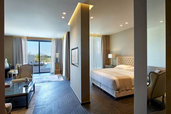 Schlafzimmer im Pelagos Suites Hotel & Spa mit großem Bett, Wohnzimmermöbeln und Aussicht.