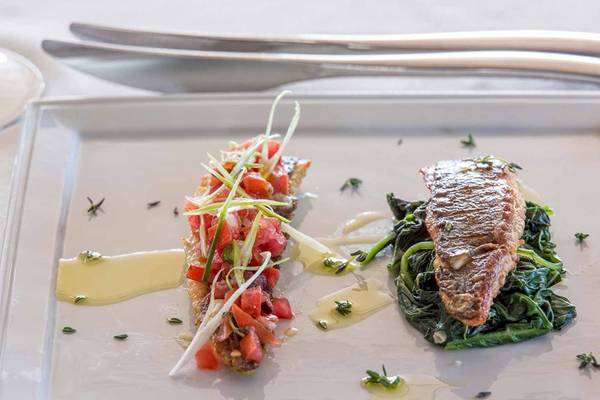 Elegantes Gericht auf weißem Teller mit Salat und Fleisch im Pelagos Suites Hotel & Spa.