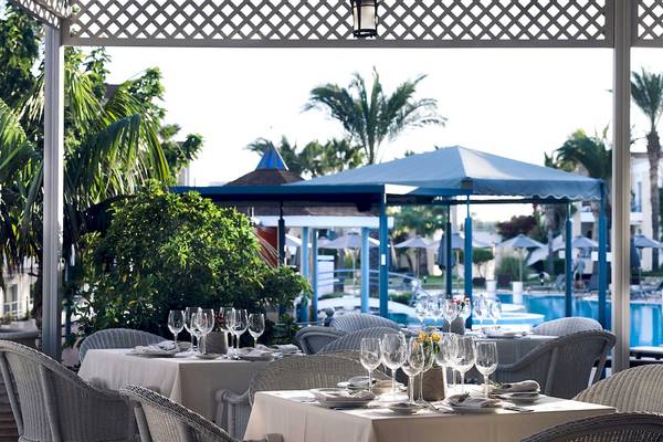 Außenbereich des Pelagos Suites Hotel & Spa Restaurants mit gedeckten Tischen und Blick auf den Pool.
