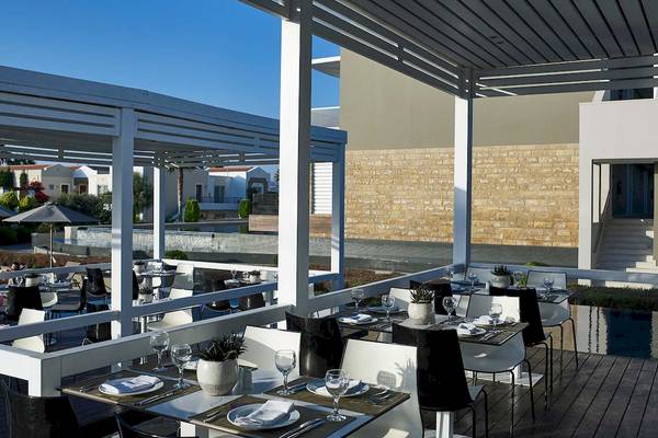Außenterrasse des Pelagos Suites Hotel & Spa mit gedeckten Tischen und Stühlen.