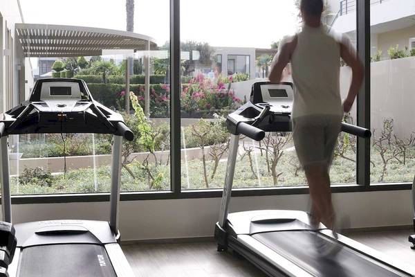 Fitnessbereich des Pelagos Suites Hotel & Spa mit zwei Laufbändern und großem Fenster.