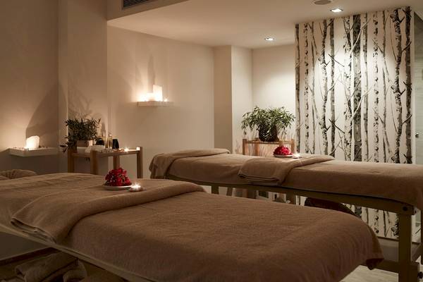 Massage-Behandlungsraum im Pelagos Suites Hotel & Spa mit zwei Massagetischen und Ambientbeleuchtung.
