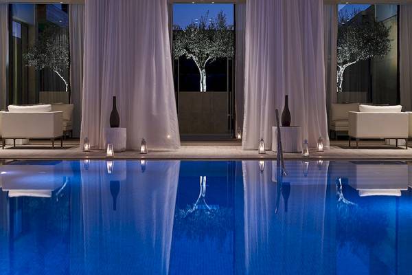 Außenpoolbereich des Pelagos Suites Hotel & Spa mit blauem Wasser und weißen Vorhängen.