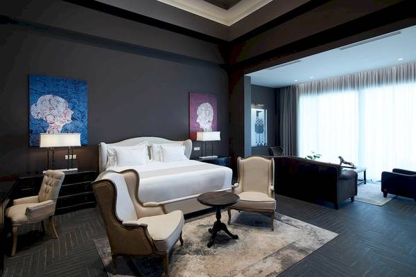 Schlafzimmer im Pelagos Suites Hotel mit großem Bett, Kunstwerken und Möbeln.