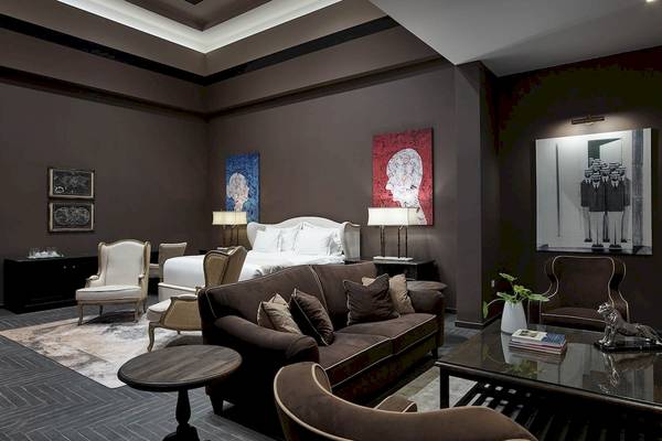 Schlafzimmer des Pelagos Suites Hotel mit Bett, Sofa, Lampen und Gemälden an der Wand.