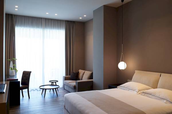 Schlafzimmer im Pelagos Suites Hotel & Spa mit Bett, Couch, Schreibtisch und Fenstern.