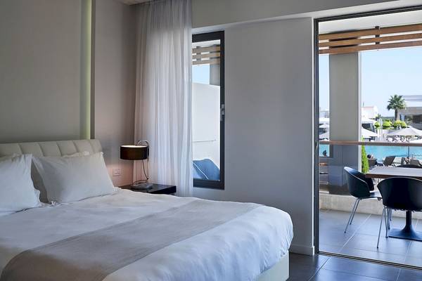 Innenansicht eines luxuriösen Schlafzimmers im Pelagos Suites Hotel & Spa mit Blick auf den Pool.