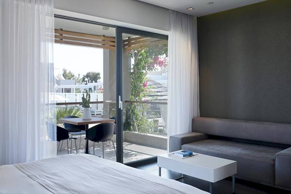 Schlafzimmer des Pelagos Suites Hotel & Spa mit Balkon, Tisch und Stühlen.